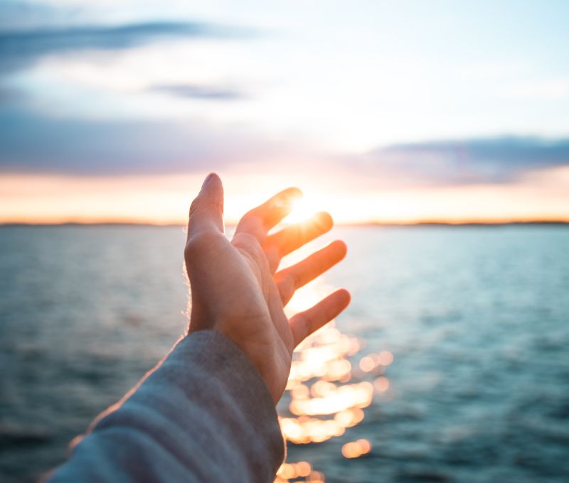 Hand streckt sich dem Horizont entgegen